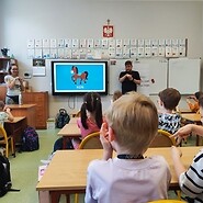 Dzieci w klasie uczą się języka migowego konia, na ekranie też obraz konia.
