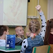 Grupa dzieci podnosi ręce do odpowiedzi