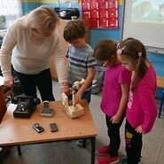 Trenerka UKE prezentuje trójce dzieci zabytkowe aparaty telefoniczne
