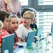 dzieci siedzą przy komputerach