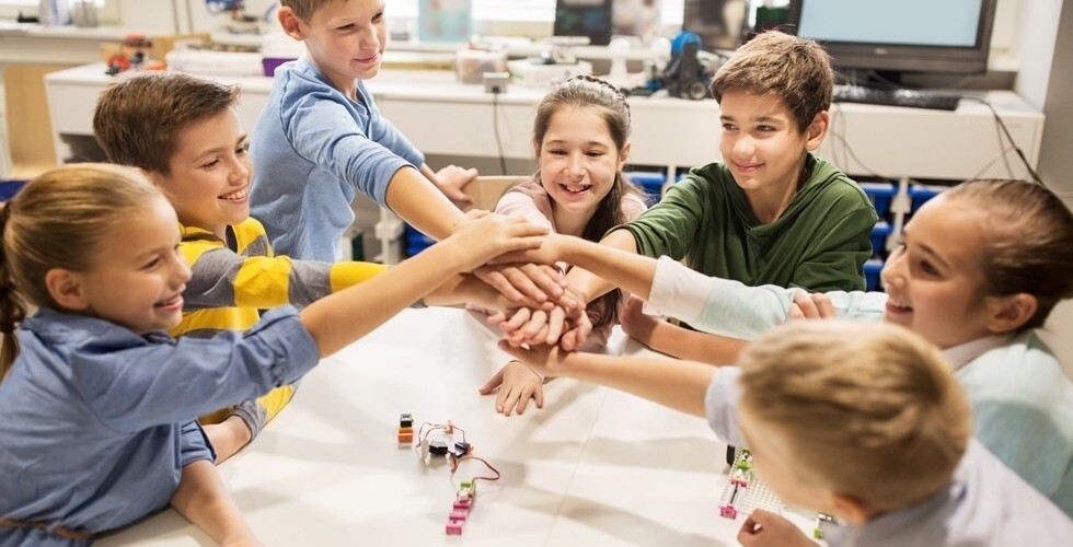 Dzieci kładą swoje dłonie jedna na drugiej