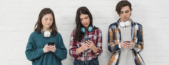Trzy młode osoby ze smartfonami