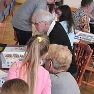 dzieci i seniorzy kodują przy stołach