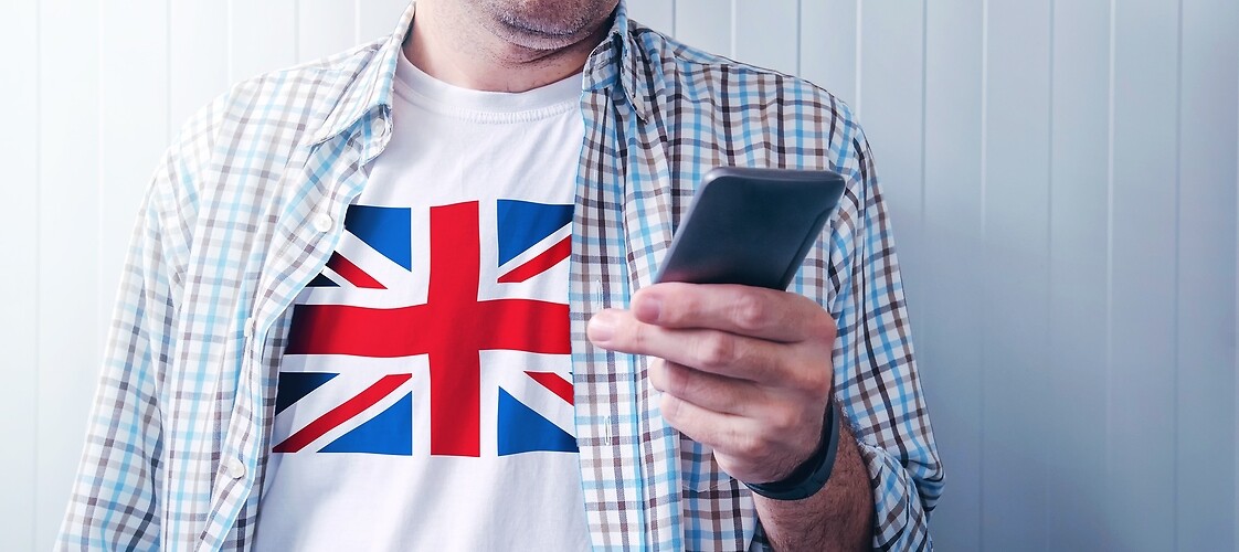 mężczyzna ze smartfonem w koszulce z flagą Wielkiej Brytanii