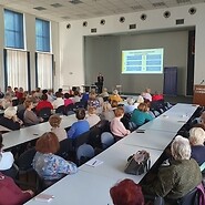 Duża grupa seniorów siedząca na sali wykładowej
