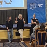 trzy kobiety stją przed sceną na sali jest widownia