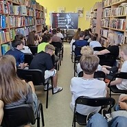 uczniowe siedzą na krzesłach, słuchają wykładu