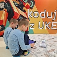 dzieci siedzą na podłodze i sterują robotem