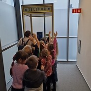 dzieci stoją przed budką telefoniczną