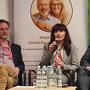 dwóch mężczyzn i jedna kobieta. Kobieta mówi do mikrofonu