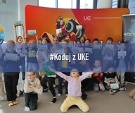 grupa dzieci na tle ścianki "koduj z UKE"