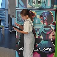 dzieci podczas nauki kodowania, w tle roll up z grafiką koduj z UKE