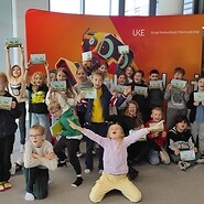 grupa dzieci na tle ścianki &quot;koduj z UKE&quot;