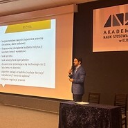 mężczyzna stoi na scenie, mówi do mikrofonu