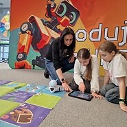 dzieci siedzą na podłodze i kodują obok nich jest kobieta