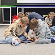 dzieci siedzą na podłodze i kodują