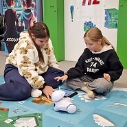 dzieci siedzą na podłodze i kodują