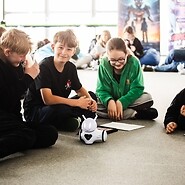 dzieci siedzą na podłodze i kodują