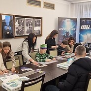 dzieci siedzą przy stołach i kodują