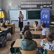 dzieci siedzą przy ławkach w sali lekcyjnej