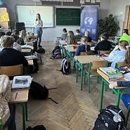 dzieci siedzą przy ławkach w sali lekcyjnej