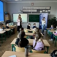 dzieci siedzą przy ławkach w sali lekcyjnej