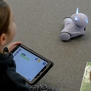 dziecko trzyma tablet w ręki, robot Prjoton srtoi na przeciwko dziecka